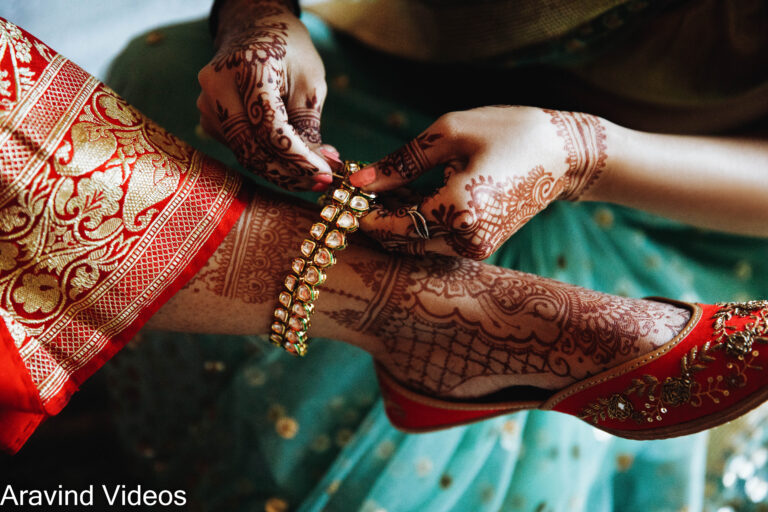 Woman puts bracelet on Hindu bride's leg